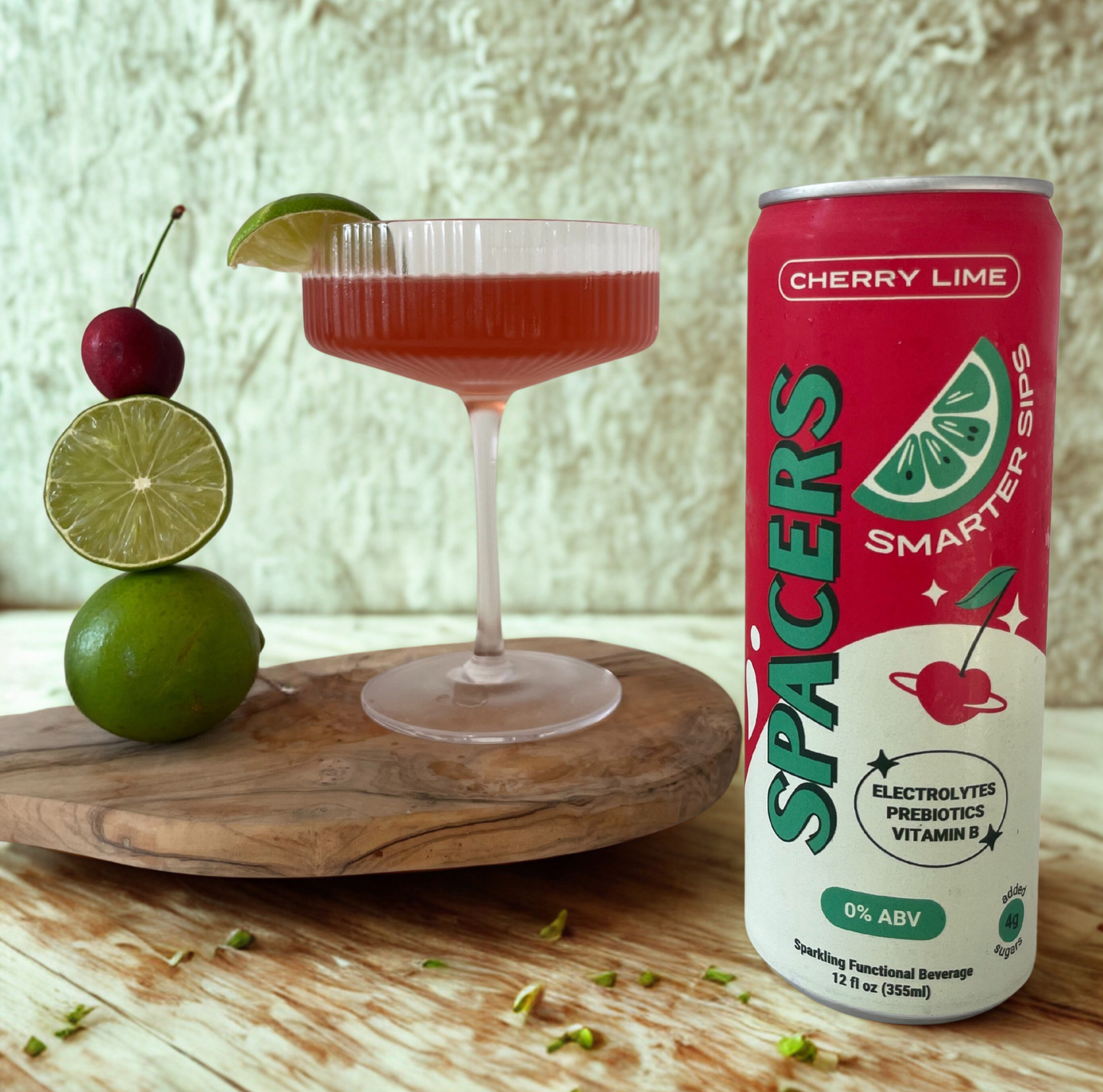 Cocktail with cherry and lime garnish next to a can of 'Spacers' Cherry Lime drink on a wooden surface.